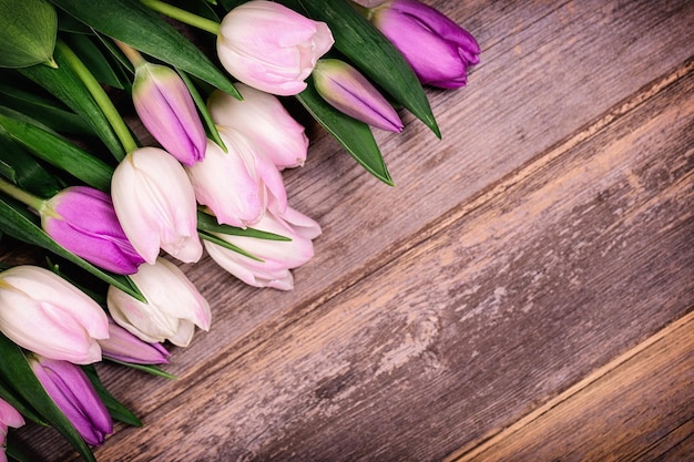 Tulipanes rosas y blancos sobre fondo de madera vieja con espacio para texto