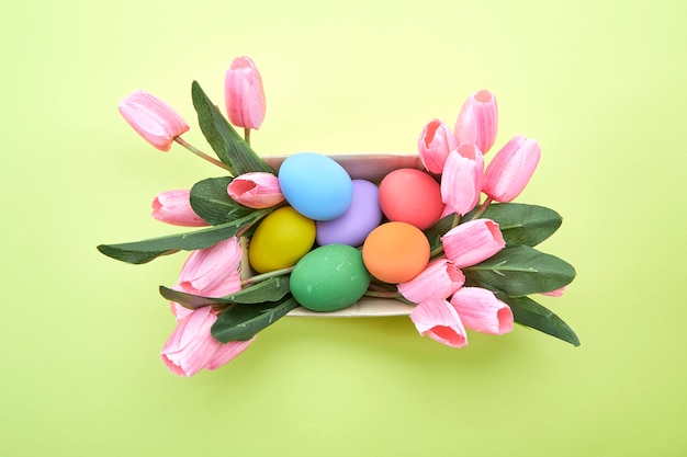 Tulipanes rosas en caja y huevo de Pascua en amarillo