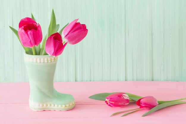 Tulipanes rosas en florero sobre fondo de madera verde