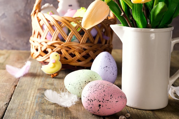 Tulipas amarelas em um vaso e ovos coloridos de Páscoa em uma mesa de madeira. Presente e ovos de Páscoa.
