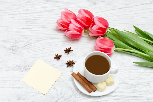 Tulipas cor de rosa, caneca de café e canela.