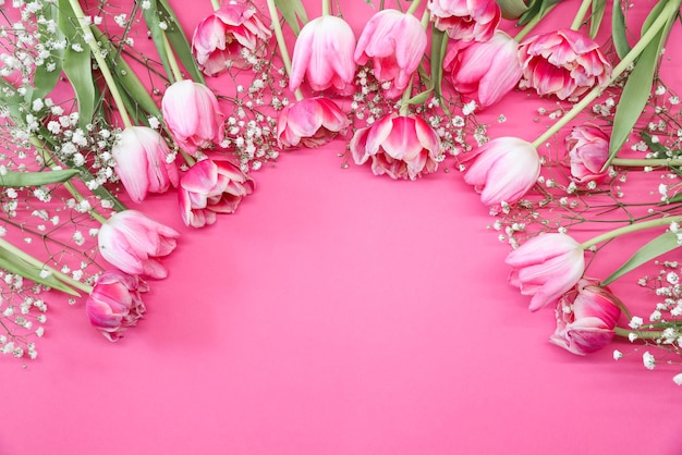 Tulipas cor de rosa e buquê de flores brancas de gypsophila em um fundo rosa Conceito de comemoração de aniversário do Dia das Mães Copiar espaço para maquete de texto