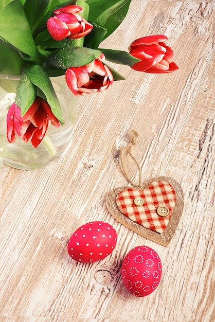 Tulipas cor de rosa e dois ovos de páscoa na mesa de madeira