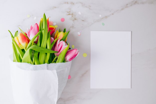 Tulipas cor de rosa e vermelhas com branco limpo em branco para o seu texto em fundo de mármore