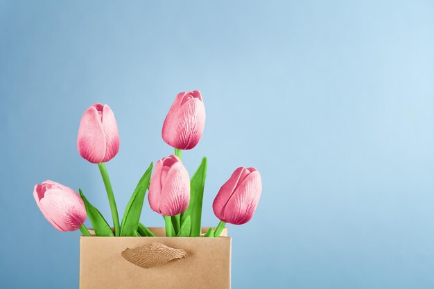 tulipas cor-de-rosa em um saco de compras em um fundo azul