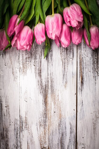 Tulipas cor de rosa em uma mesa de madeira branca surrada