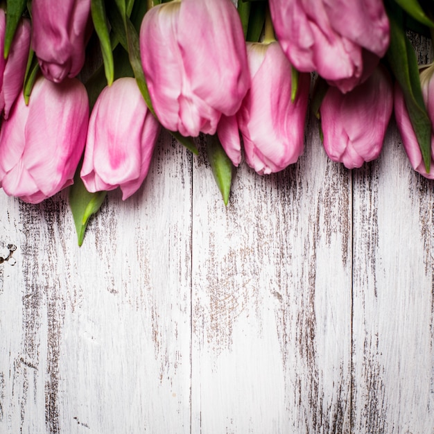 Tulipas cor de rosa em uma mesa de madeira branca surrada