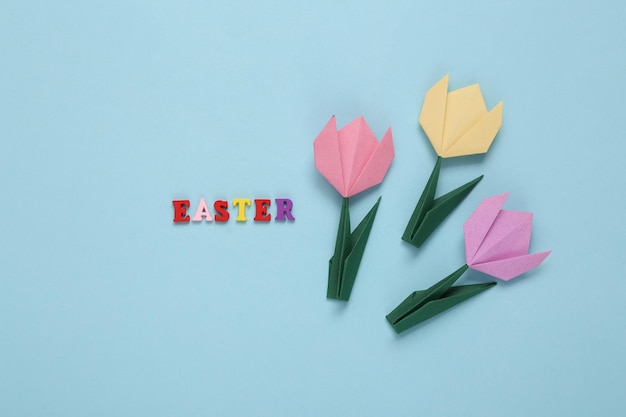 Tulipas de origami e palavra páscoa em fundo azul composição de primavera de páscoa