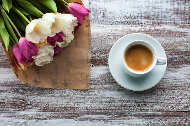 Tulipas e cafés isolados em uma mesa de madeira