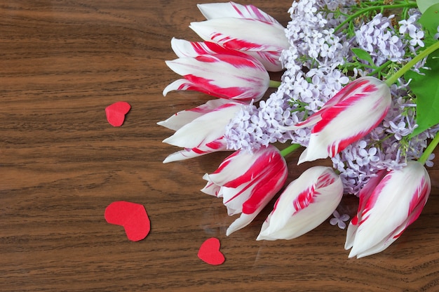 Tulipas e flores lilás e coração de papel vermelho em fundo de madeira