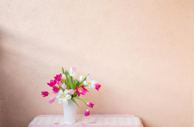 tulipas em vaso na mesa na parede de fundo