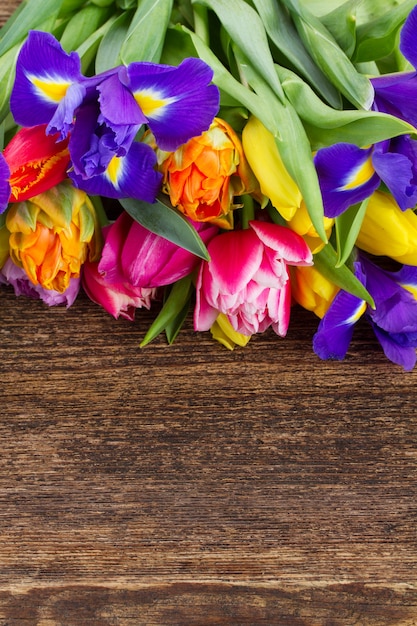 Tulipas frescas da primavera e íris em madeira