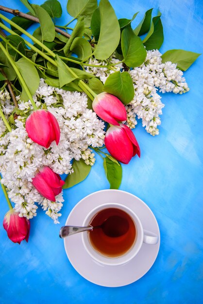 Tulipas lilases e vermelhas brancas e chá em um fundo azul, para design de cartão postal, embalagem e arte da capa