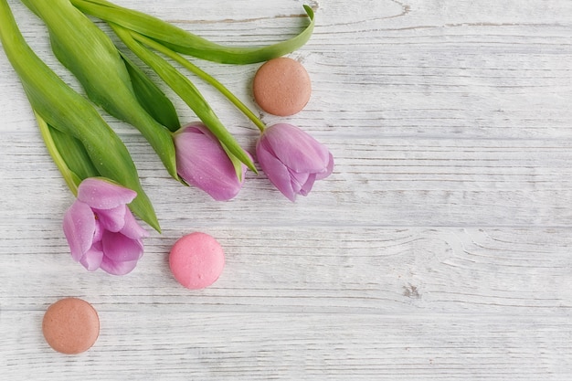 Tulipas roxas e macaroons franceses pastel doces na mesa de madeira