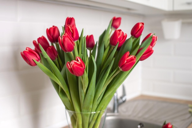 Tulipas vermelhas de kung fu estão em um vaso de vidro na mesa da cozinha Buquê de flores