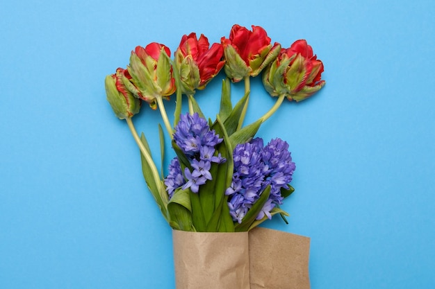 Tulipas vermelhas e flores de jacinto azul em buquê em fundo azul colorido