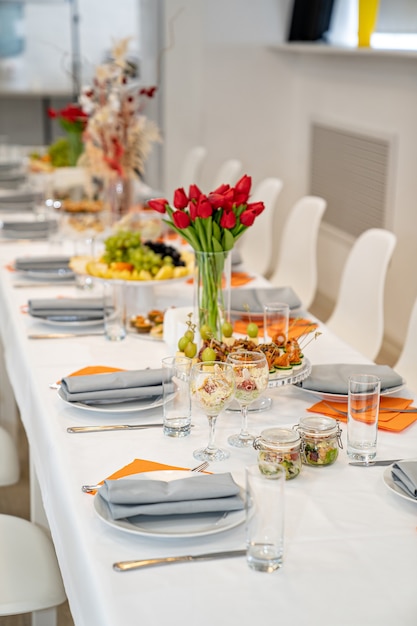 Tulpen auf festlich gedecktem Tisch mit Vorspeisen Häppchen Salate in Gläsern