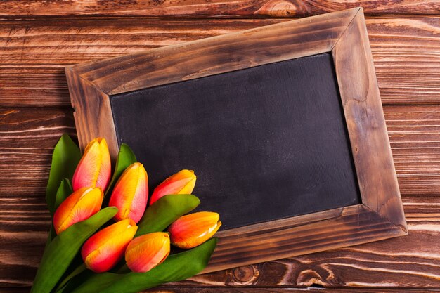 Tulpen mit Tafel auf Holzuntergrund - Frühlingsgrüße
