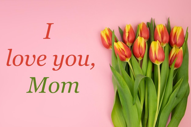 Tulpen sind gelbrot auf einem rosa Hintergrund und einem rotgrünen Text ICH LIEBE DICH MOM