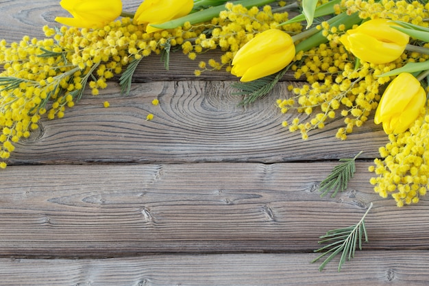 Tulpen und Mimose auf dunklem altem hölzernem Hintergrund