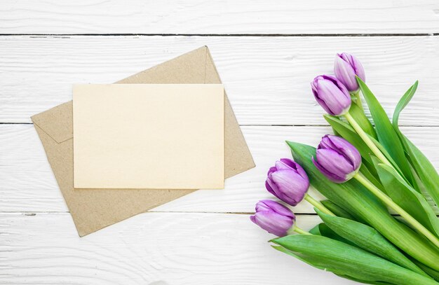 Tulpenbüchel und Umschlag auf weißem Holzhintergrund