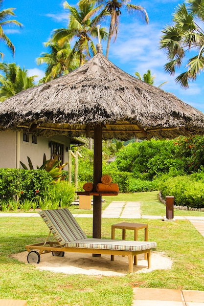 Foto tumbona bajo una sombrilla en la piscina del hotel en seychelles