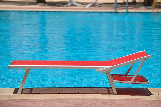 Tumbona vacía en el lado de la piscina en el resort de verano Vacaciones y concepto de escapada