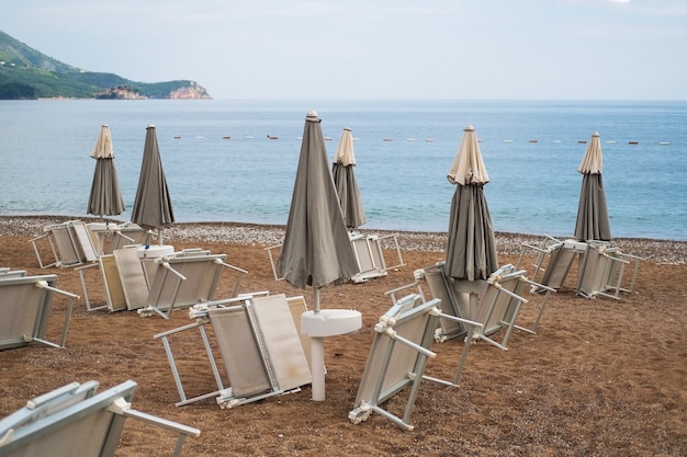 Tumbonas invertidas bajo las sombrillas en la playa de guijarros junto al mar