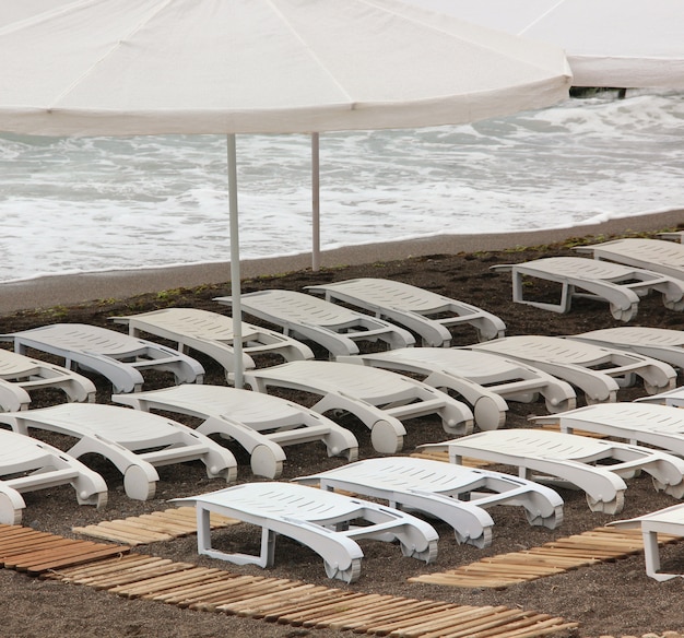 Tumbonas de plástico blanco en la playa.