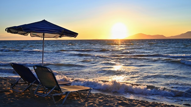 Tumbonas y sombrillas en la playa al atardecer junto al mar Hermoso concepto para vacaciones de verano y viajes