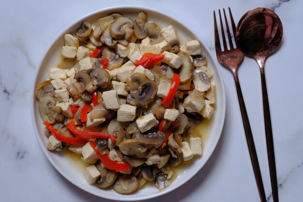 tumis jamur tahu páprica. refogue o tofu, o pimentão vermelho e o cogumelo. culinária vegana. comida saudável.