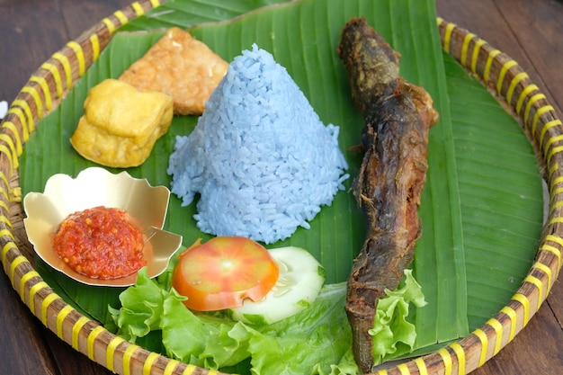 Tumpeng lele goreng. arroz en forma de cono con guisante mariposa, bagre frito, tofu tempeh frito, sambal.