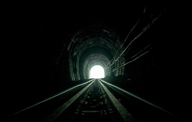 Túnel de trem. Ferrovia velha na caverna. Esperança de vida no final do caminho.