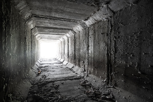 Túnel de hormigón cuadrado vacío con luz en el extremo alcantarillado seco