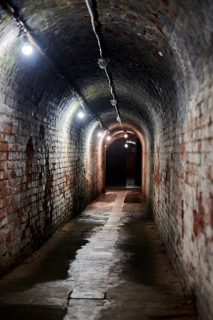 Túnel de ladrillo en el antiguo fuerte alemán, corredor de loft de ladrillo rojo con cableado antiguo, sótano industrial de la base militar secreta. Pasaje secreto de la vieja mansión. Fuerte No. 5 Rey Federico Guillermo III