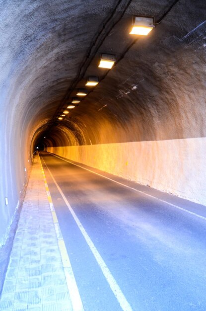 Túnel oscuro subterráneo y carretera incandescente iluminada