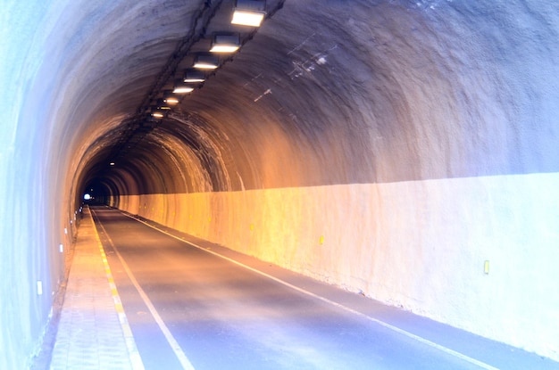 Túnel oscuro subterráneo y carretera incandescente iluminada