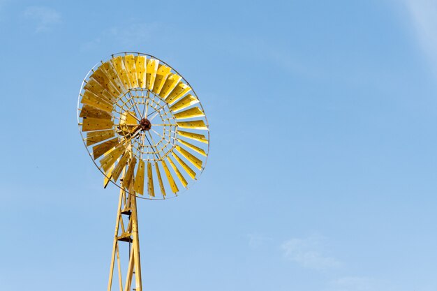 Turbina eólica amarela em fundo de céu azul