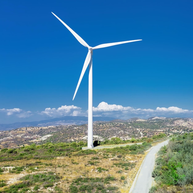 Turbina eólica no topo da colina no parque eólico Oreites em Chipre contra o céu azul, vista de drone