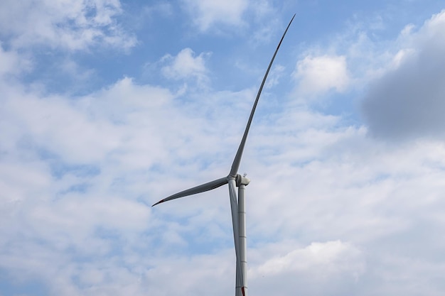 Turbina de generador de viento contra el cielo azul nublado