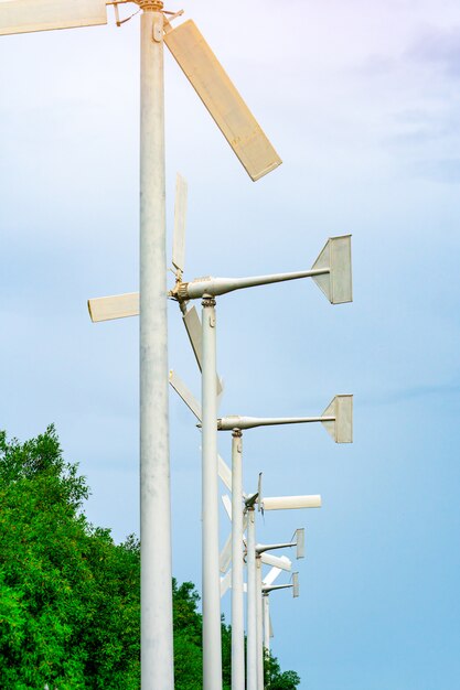 Turbina de viento con cielo azul y nubes blancas cerca de árbol verde. Energía eólica en el parque eólico eco. Recursos sostenibles