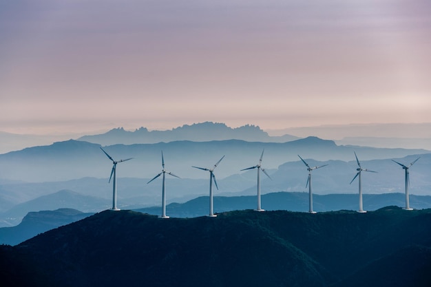 Turbinas eólicas na montanha contra o céu durante o pôr do sol