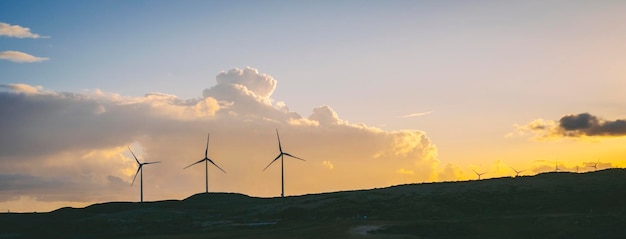 Turbinas de viento en el campo contra un cielo azul con fondo de nubes Concepto de producción de energía verde y buen estilo de vida ambiental futuro Granja de electricidad renovable con molinos de viento