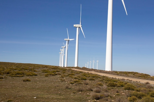 Turbinas de viento en una divisoria montañosa que produce electricidad por la fuerza del viento