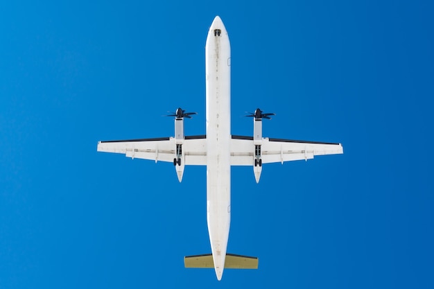 Turboprop-Flugzeuge mit Propellermotoren auf Flügeln vor der Landung auf einer Landebahn am Flughafen gegen einen blauen Himmel.