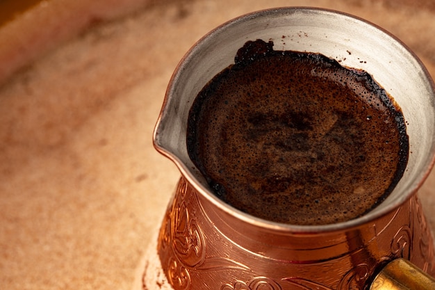 Turco de cobre con café en la arena de cerca.