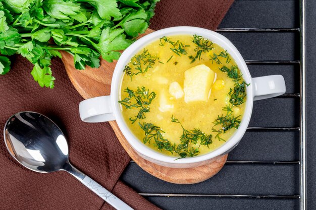 Tureen com sopa de ervilha com um monte de salsa fresca e uma colher na mesa