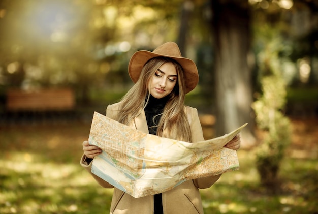 Turismo de outono. Jovem viajante feminina atraente é guiada pelo mapa da cidade. Linda garota procurando direção na cidade. Feriados e conceito de turismo