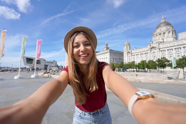 Turismo em Liverpool UK Linda jovem tira foto de selfie em frente ao Pier Head com The Three Graces no centro da cidade de Liverpool Inglaterra