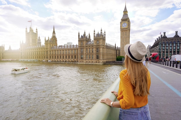 Turismo em londres vista traseira da garota viajante apreciando a vista do palácio de westminster e ponte no tamisa com a famosa torre big ben em londres, reino unido